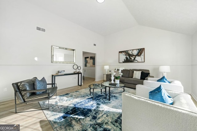 living room with lofted ceiling, wood finished floors, visible vents, and baseboards