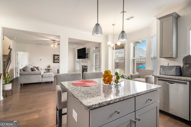 kitchen featuring light stone counters, open floor plan, a center island, dishwasher, and pendant lighting