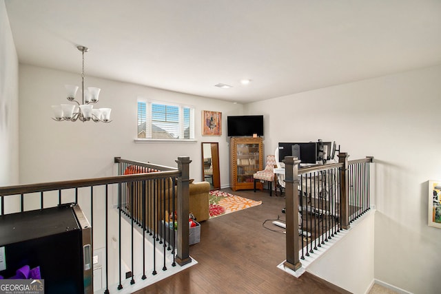 hallway featuring a notable chandelier, baseboards, dark wood-style flooring, and an upstairs landing