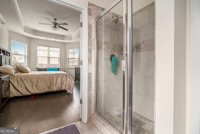 ensuite bathroom featuring a tray ceiling, wood finished floors, a shower stall, and ensuite bathroom