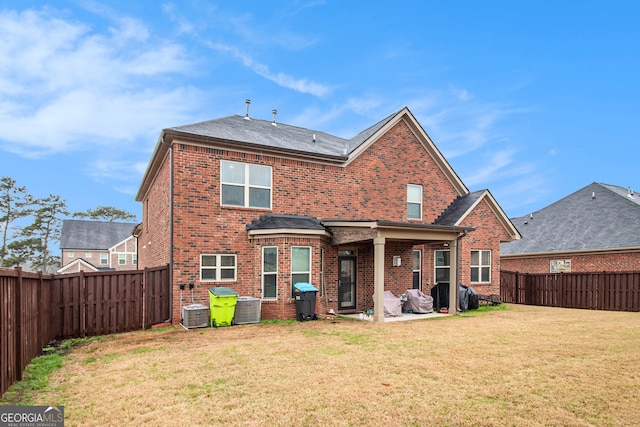 back of property featuring brick siding, a lawn, and a fenced backyard