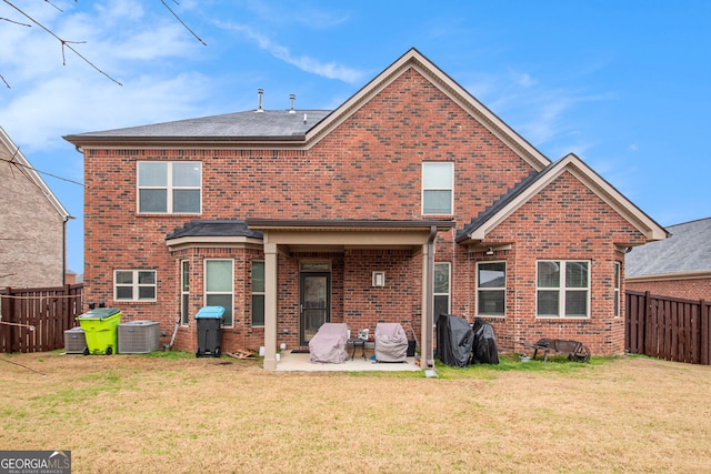 rear view of property with brick siding, a patio, and a lawn