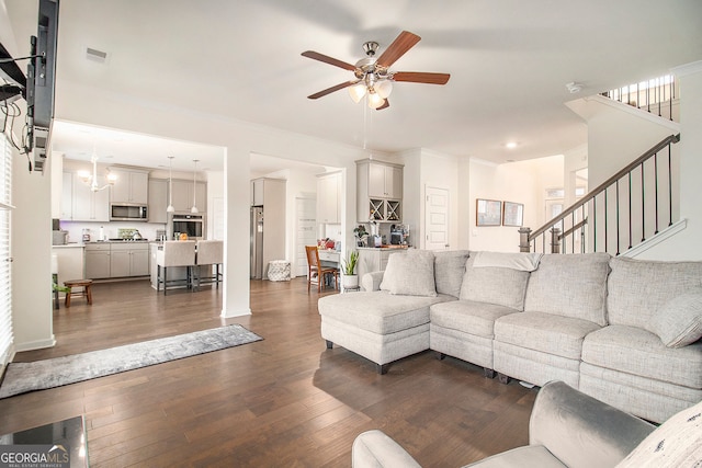 living area featuring visible vents, a ceiling fan, dark wood-style flooring, stairs, and crown molding