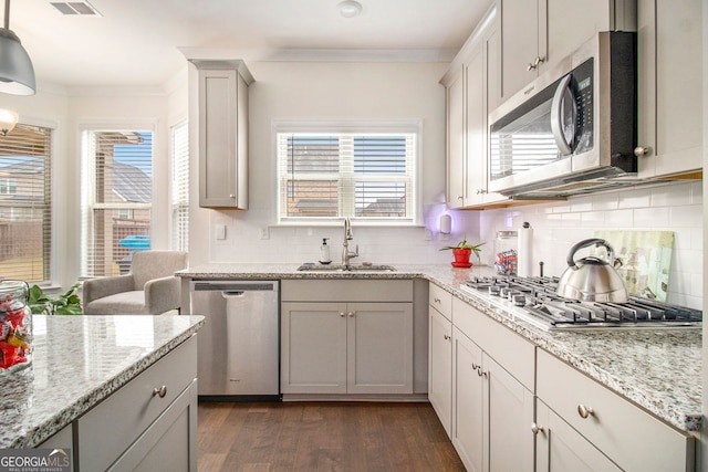 kitchen with stainless steel appliances, plenty of natural light, a sink, and ornamental molding