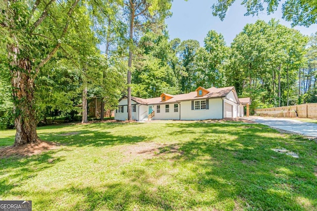 ranch-style home featuring a garage, driveway, a front lawn, and fence