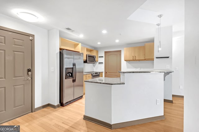 kitchen featuring visible vents, dark stone counters, hanging light fixtures, stainless steel appliances, and light wood-style floors