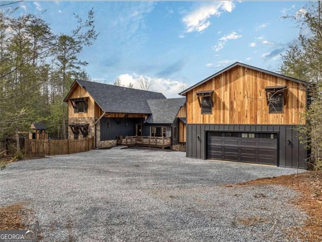 view of front facade featuring roof with shingles, driveway, an attached garage, and fence