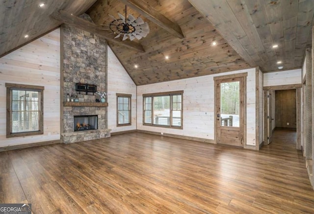 unfurnished living room with wooden ceiling, beamed ceiling, wood finished floors, a stone fireplace, and high vaulted ceiling