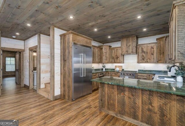 kitchen with wood ceiling, a sink, wood finished floors, high quality appliances, and a peninsula