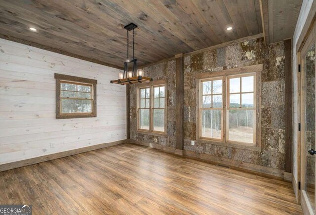 unfurnished dining area with a chandelier, wooden ceiling, wood finished floors, and a wealth of natural light