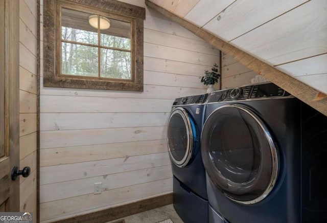 washroom with wooden walls, laundry area, and washer and clothes dryer