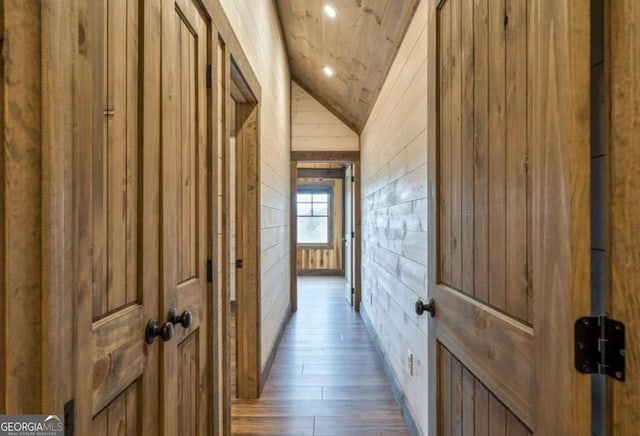 hall with lofted ceiling, dark wood-style flooring, and wood walls