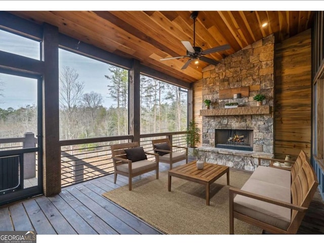 interior space with wood ceiling, an outdoor stone fireplace, vaulted ceiling, and ceiling fan