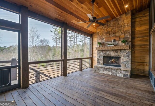 wooden terrace featuring ceiling fan and an outdoor stone fireplace