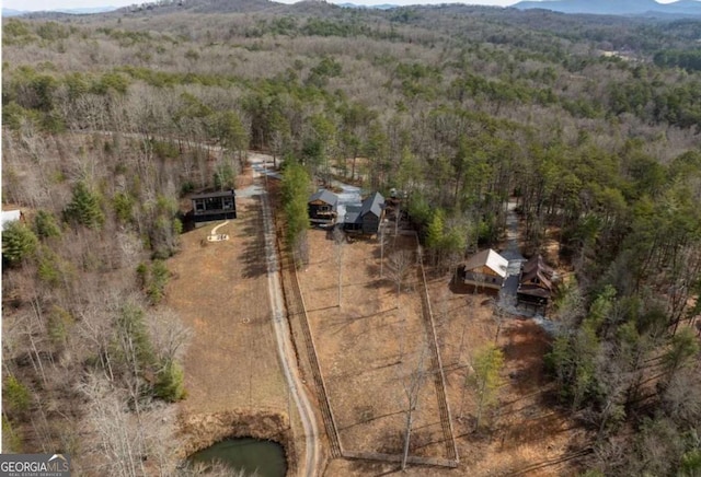 drone / aerial view featuring a wooded view and a water and mountain view