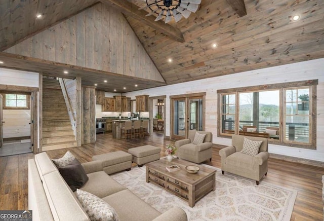 living area featuring stairs, high vaulted ceiling, light wood finished floors, and a ceiling fan