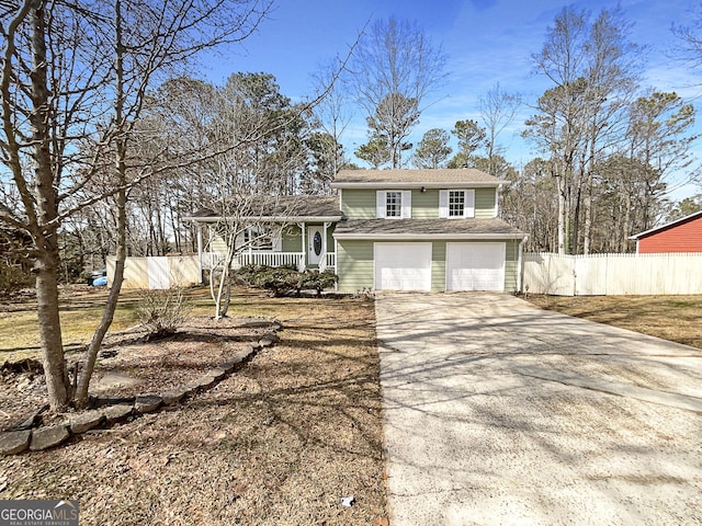 split level home with driveway, a porch, an attached garage, and fence