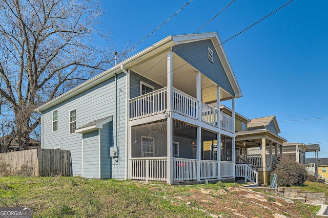 rear view of property featuring a balcony, a sunroom, fence, and a ceiling fan