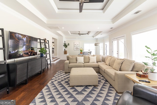 living area featuring a tray ceiling, crown molding, visible vents, dark wood-type flooring, and ceiling fan