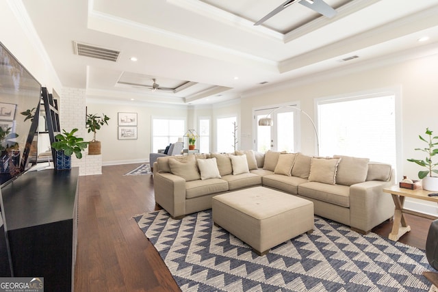 living area with a raised ceiling, visible vents, ceiling fan, and a healthy amount of sunlight