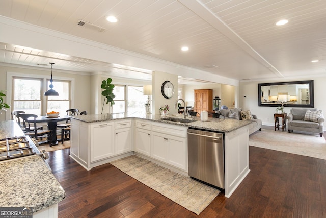 kitchen featuring white cabinets, open floor plan, hanging light fixtures, stainless steel dishwasher, and a sink