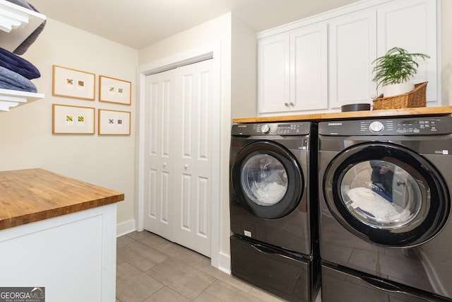 washroom featuring light tile patterned floors, washing machine and clothes dryer, cabinet space, and baseboards