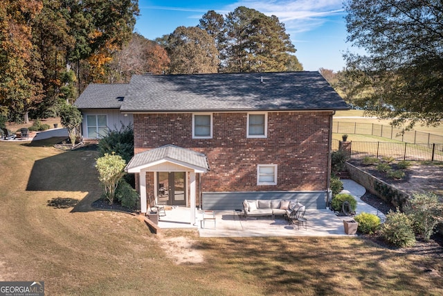 back of property with an outdoor hangout area, a patio, brick siding, and a yard