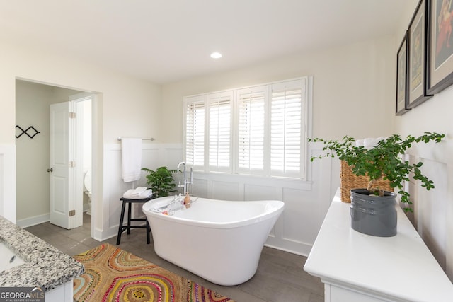 full bath featuring a wainscoted wall, recessed lighting, a decorative wall, vanity, and a freestanding tub