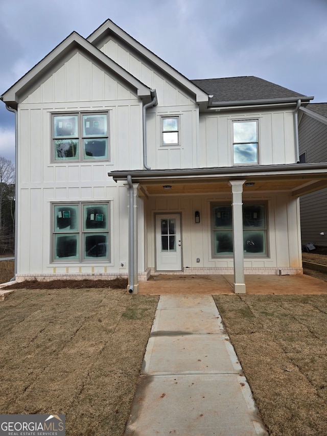 modern farmhouse featuring board and batten siding, a shingled roof, a front lawn, and a porch