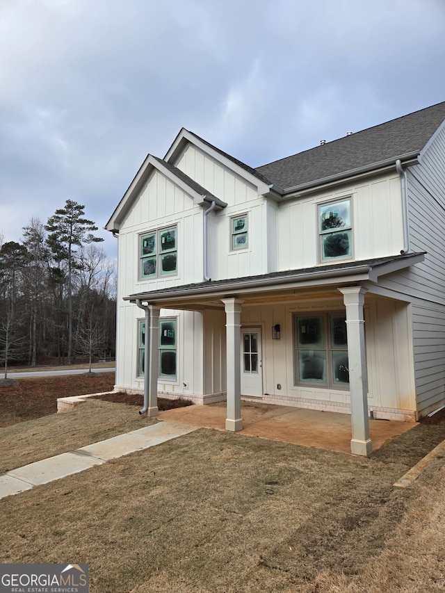 modern farmhouse featuring a shingled roof, board and batten siding, and a front yard