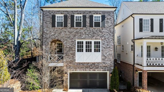 view of front of house featuring an attached garage, a shingled roof, concrete driveway, and brick siding