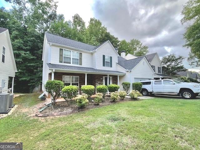 view of front of home with covered porch, a front lawn, and central air condition unit