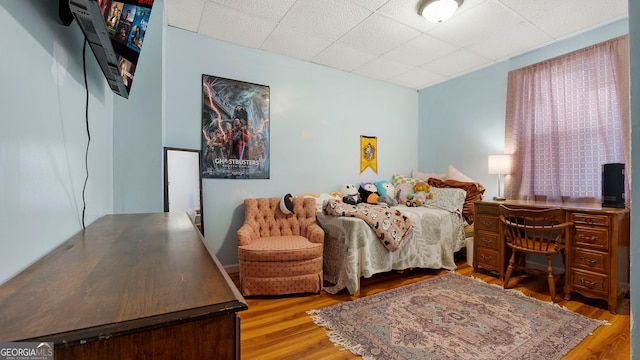 bedroom featuring a drop ceiling and wood finished floors