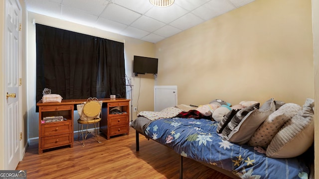 bedroom featuring a drop ceiling and light wood finished floors