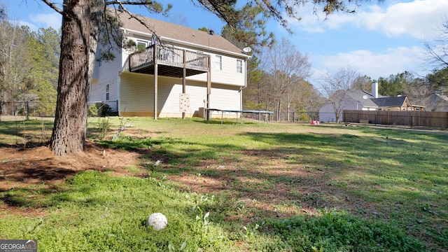 rear view of property featuring a balcony, fence, and a yard