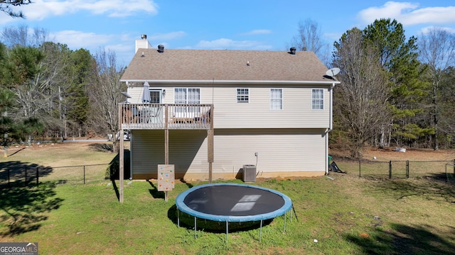 back of property featuring a trampoline, fence, a chimney, and a lawn