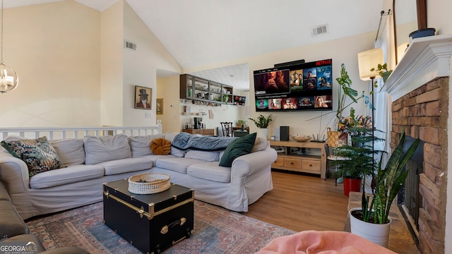 living room featuring dark wood finished floors, a fireplace, visible vents, an inviting chandelier, and high vaulted ceiling