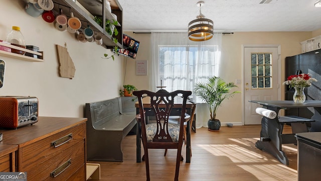 dining space featuring light wood-style flooring, baseboards, and a textured ceiling