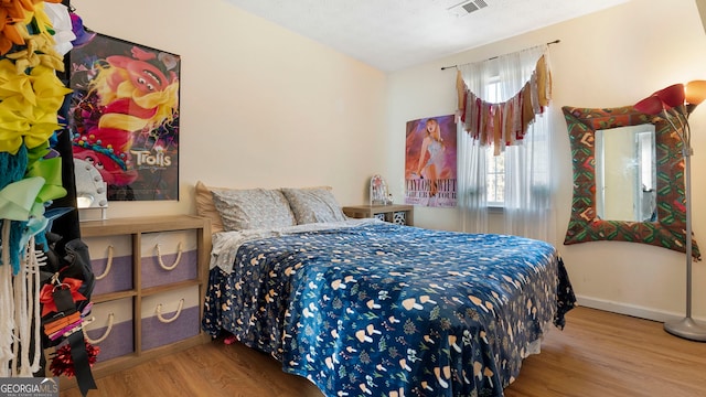 bedroom with visible vents, baseboards, and wood finished floors