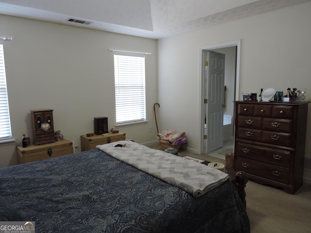 bedroom with visible vents, a textured ceiling, and light colored carpet