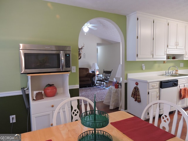 kitchen with light countertops, stainless steel microwave, a sink, and white cabinets