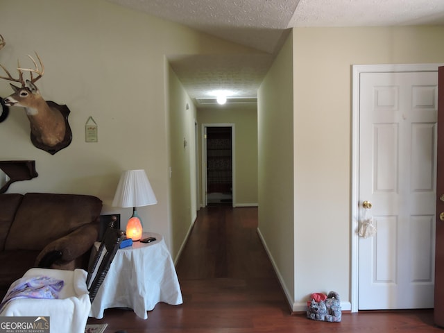 hall featuring baseboards, dark wood-type flooring, and a textured ceiling