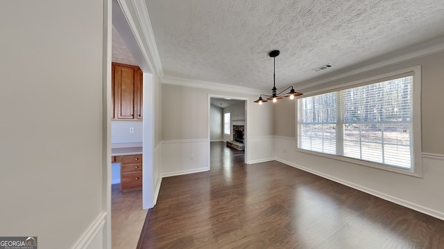 unfurnished dining area with dark wood-style floors, crown molding, visible vents, and a textured ceiling