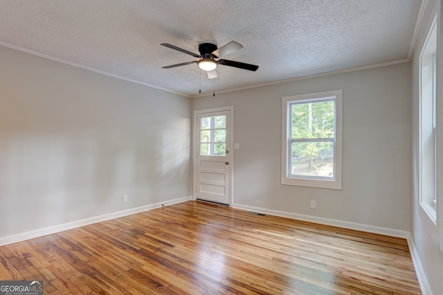 spare room with a ceiling fan, light wood-style flooring, baseboards, and crown molding