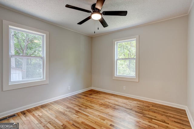 empty room featuring light wood finished floors, baseboards, visible vents, and a textured ceiling