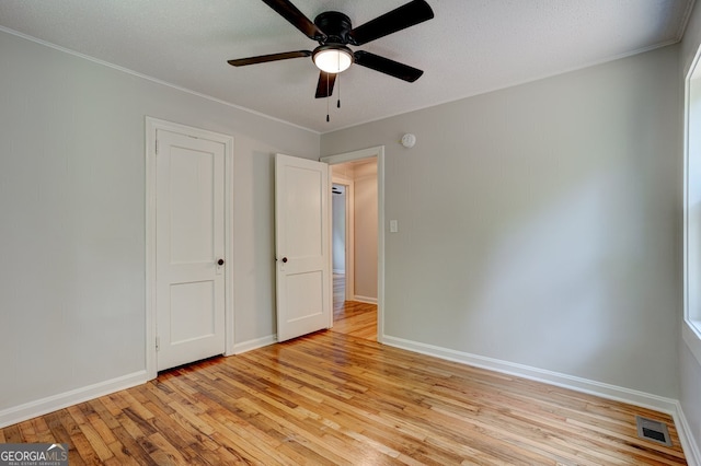 unfurnished bedroom featuring light wood finished floors, baseboards, visible vents, and crown molding