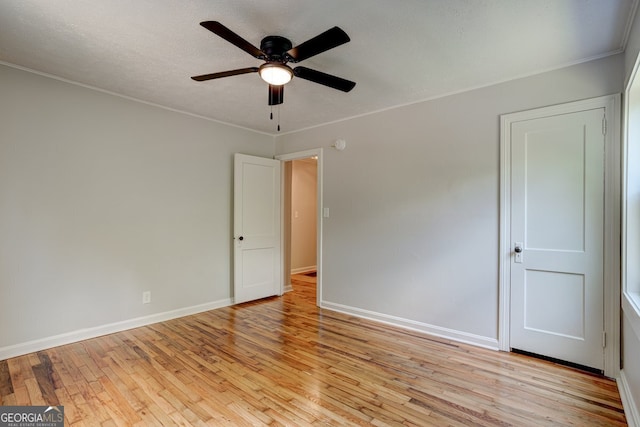 spare room featuring light wood-type flooring, a textured ceiling, baseboards, and a ceiling fan