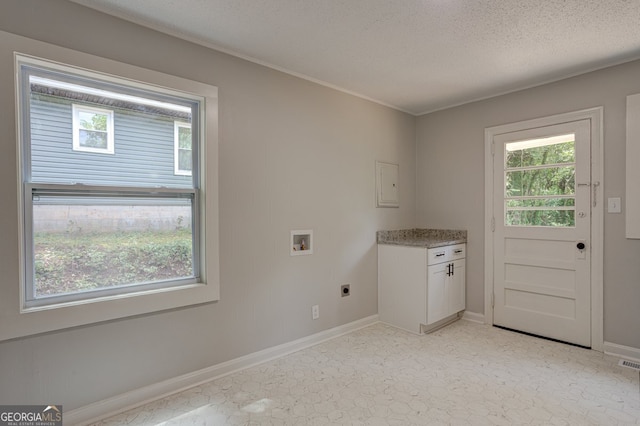 laundry area featuring a textured ceiling, hookup for a washing machine, hookup for an electric dryer, baseboards, and cabinet space