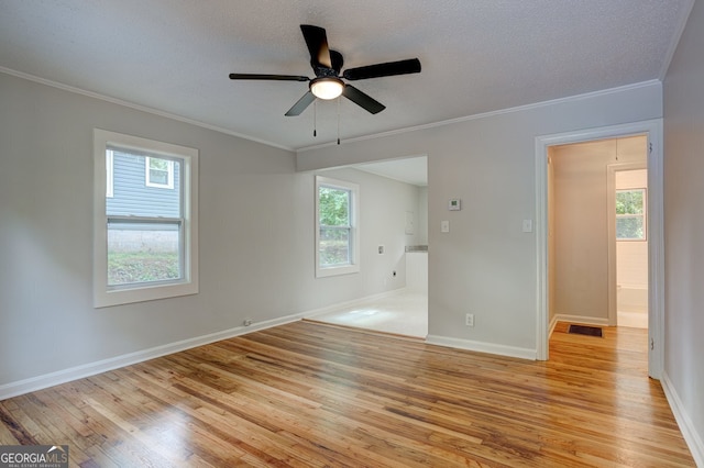 unfurnished bedroom with a textured ceiling, light wood finished floors, multiple windows, and ornamental molding