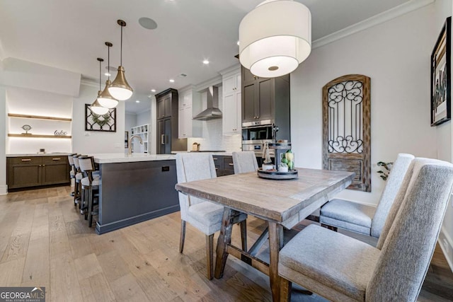 dining room featuring light wood-style floors, crown molding, and recessed lighting